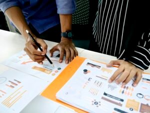 Eine Person in blauem Hemd schreibt mit einem Stift auf weißes Papier an einem Schreibtisch