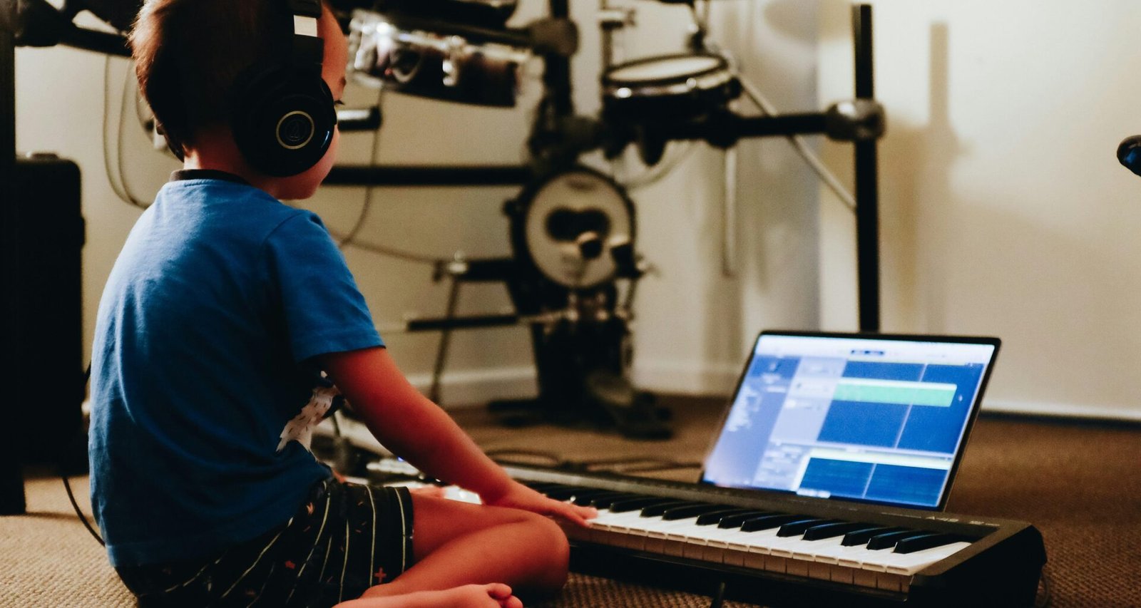 Eine Person mit blauem Hemd sitzt an einem Klavier und spielt, Fokus liegt auf den Händen auf den Tasten.