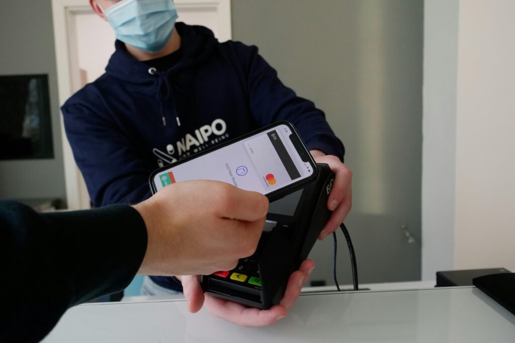 Person trägt einen schwarz-weißen Nike-Hoodie und hält ein schwarzes iPhone 4 in der Hand vor neutralem Hintergrund