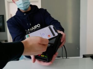 Person trägt einen schwarz-weißen Nike-Hoodie und hält ein schwarzes iPhone 4 in der Hand vor neutralem Hintergrund