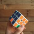 Eine Person hält einen klassischen 3x3 Rubik's Cube in den Händen, Fokus auf das bunte Puzzle und die Handhaltung.