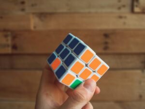 Eine Person hält einen klassischen 3x3 Rubik's Cube in den Händen, Fokus auf das bunte Puzzle und die Handhaltung.