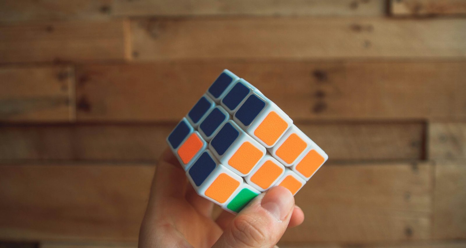 Eine Person hält einen klassischen 3x3 Rubik’s Cube in den Händen, Fokus auf das bunte Puzzle und die Finger.