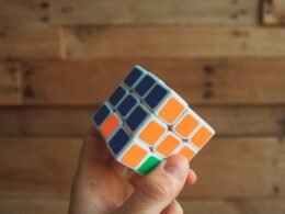 Eine Person hält einen klassischen 3x3 Rubik’s Cube in den Händen, Fokus auf das bunte Puzzle und die Finger.