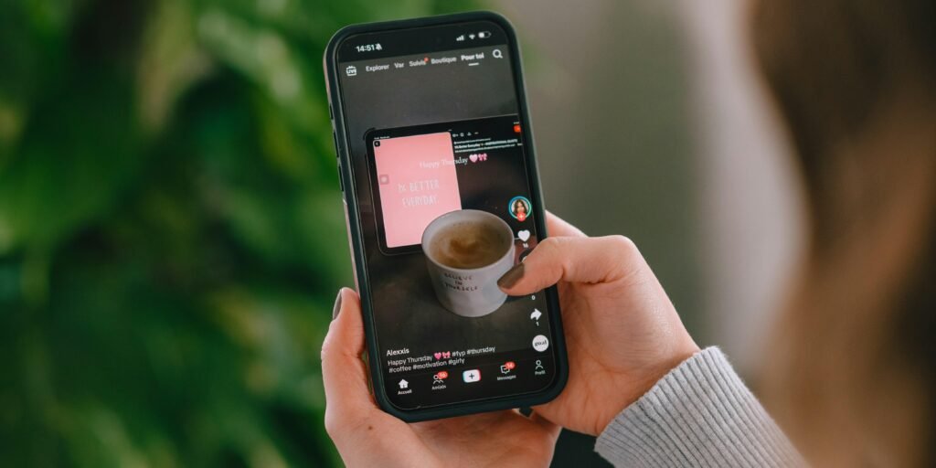 Person hält ein Smartphone, auf dem eine Kaffeetasse auf dem Bildschirm angezeigt wird, Nahaufnahme der Hand mit Handy