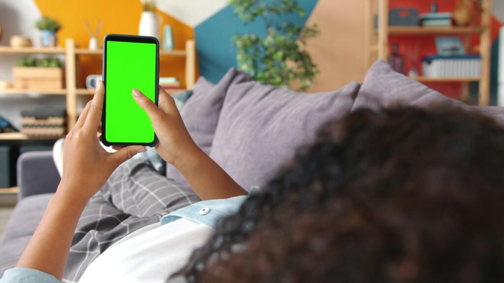 Person hält ein Smartphone mit grünem Screen in der Hand – ideal für Technologie- und Marketingthemen.