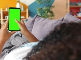 Person hält ein Smartphone mit grünem Screen in der Hand – ideal für Technologie- und Marketingthemen.