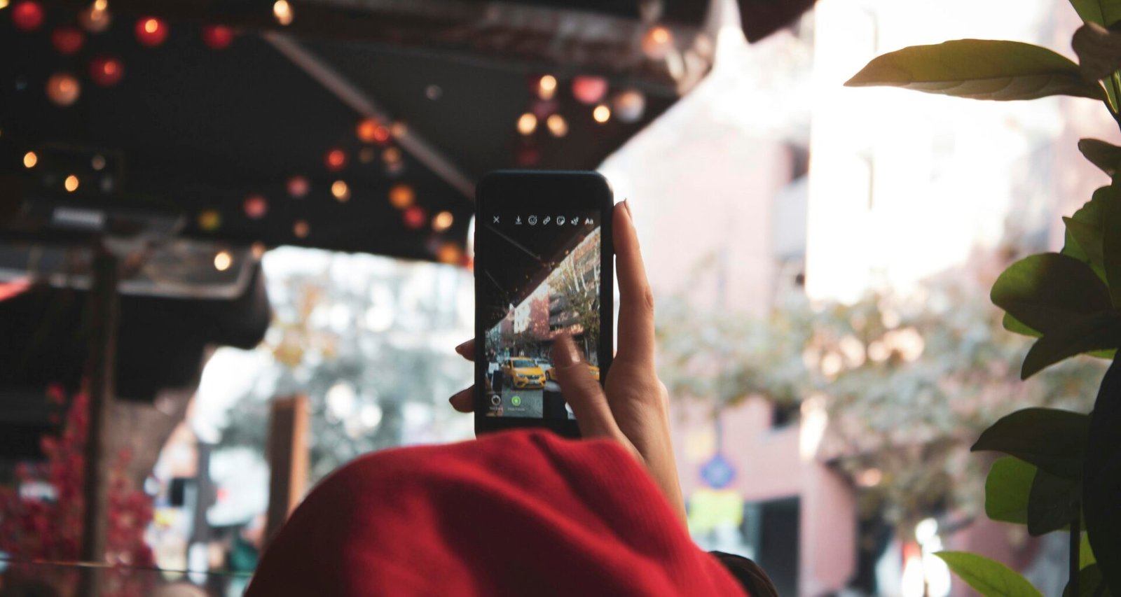 Person hält ein eingeschaltetes schwarzes Smartphone in der Hand, Fokus auf das Gerät, Technologie-Kontext