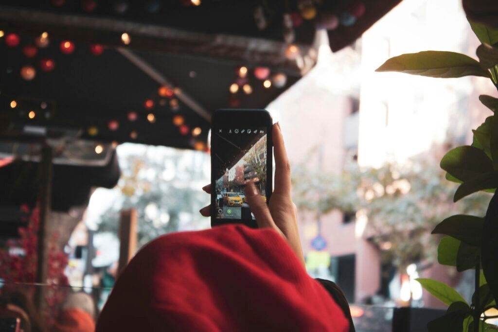 Eine Person hält ein eingeschaltetes schwarzes Smartphone in der Hand, Fokus auf das Gerät und die Nutzung im Alltag