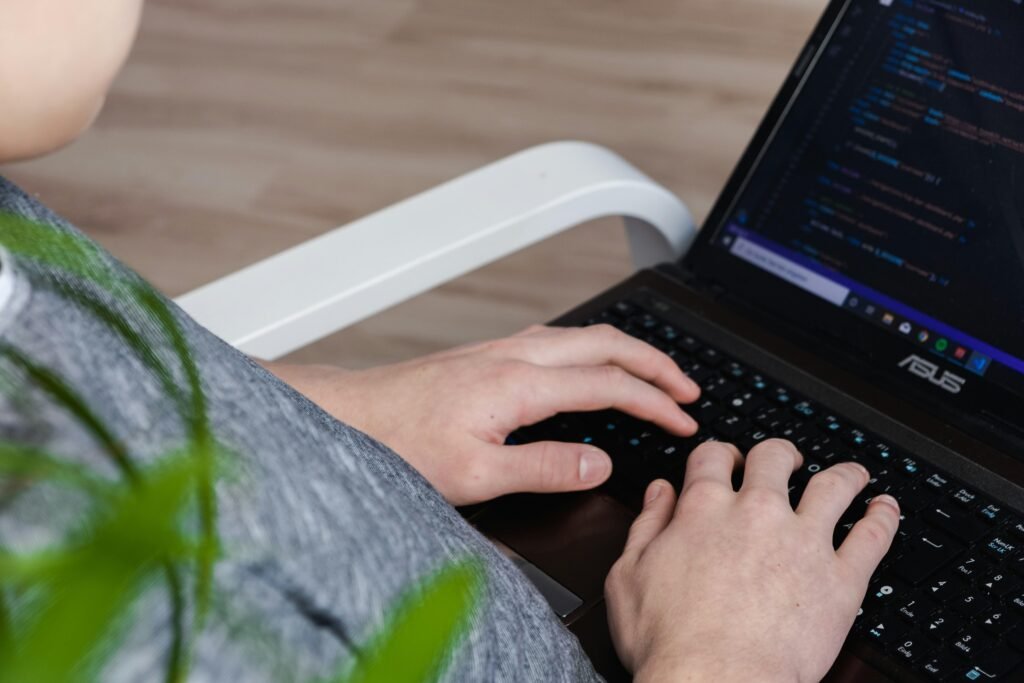 Person mit schwarzem Asus Laptop bei der Arbeit, modernes Notebook auf einem Tisch in alltäglicher Nutzung