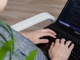 Person mit schwarzem Asus Laptop bei der Arbeit, modernes Notebook auf einem Tisch in alltäglicher Nutzung