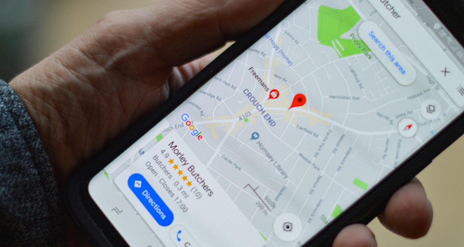 Nahaufnahme einer Person, die ein schwarzes Smartphone mit einer Hand hält, Technologie und Alltag im Fokus