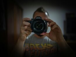 Eine Person hält eine schwarze Nikon DSLR Kamera in den Händen – moderner Ansatz für Technik- und Fotografieartikel