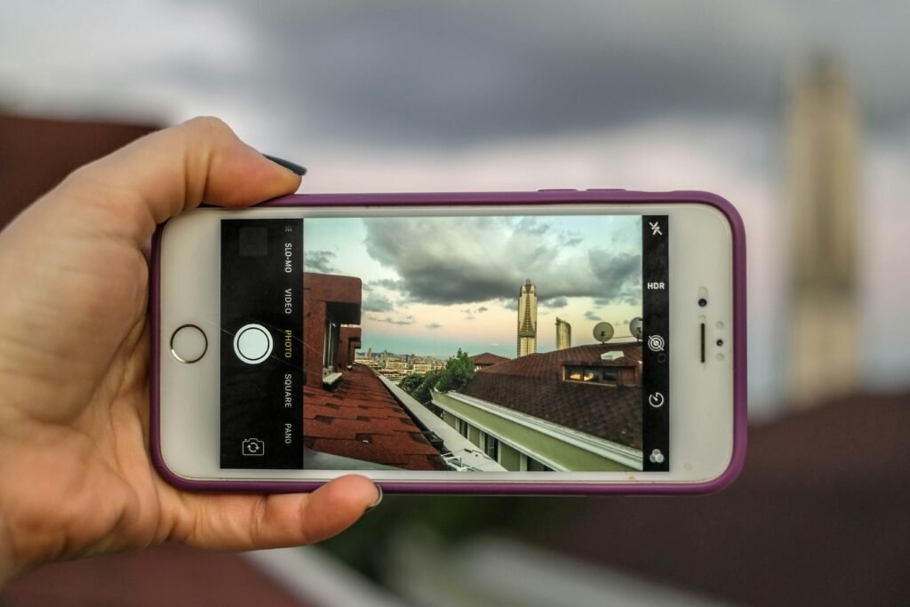 Person hält ein silbernes iPhone 6 mit violetter Schutzhülle in der Hand, Fokus liegt auf dem Smartphone