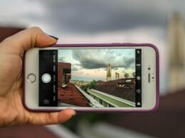 Person hält ein silbernes iPhone 6 mit violetter Schutzhülle in der Hand, Fokus liegt auf dem Smartphone