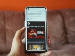 Person hält ein weißes Samsung Android Smartphone in der Hand, Fokus auf Gerät und Fingern, technisches Alltagsbild