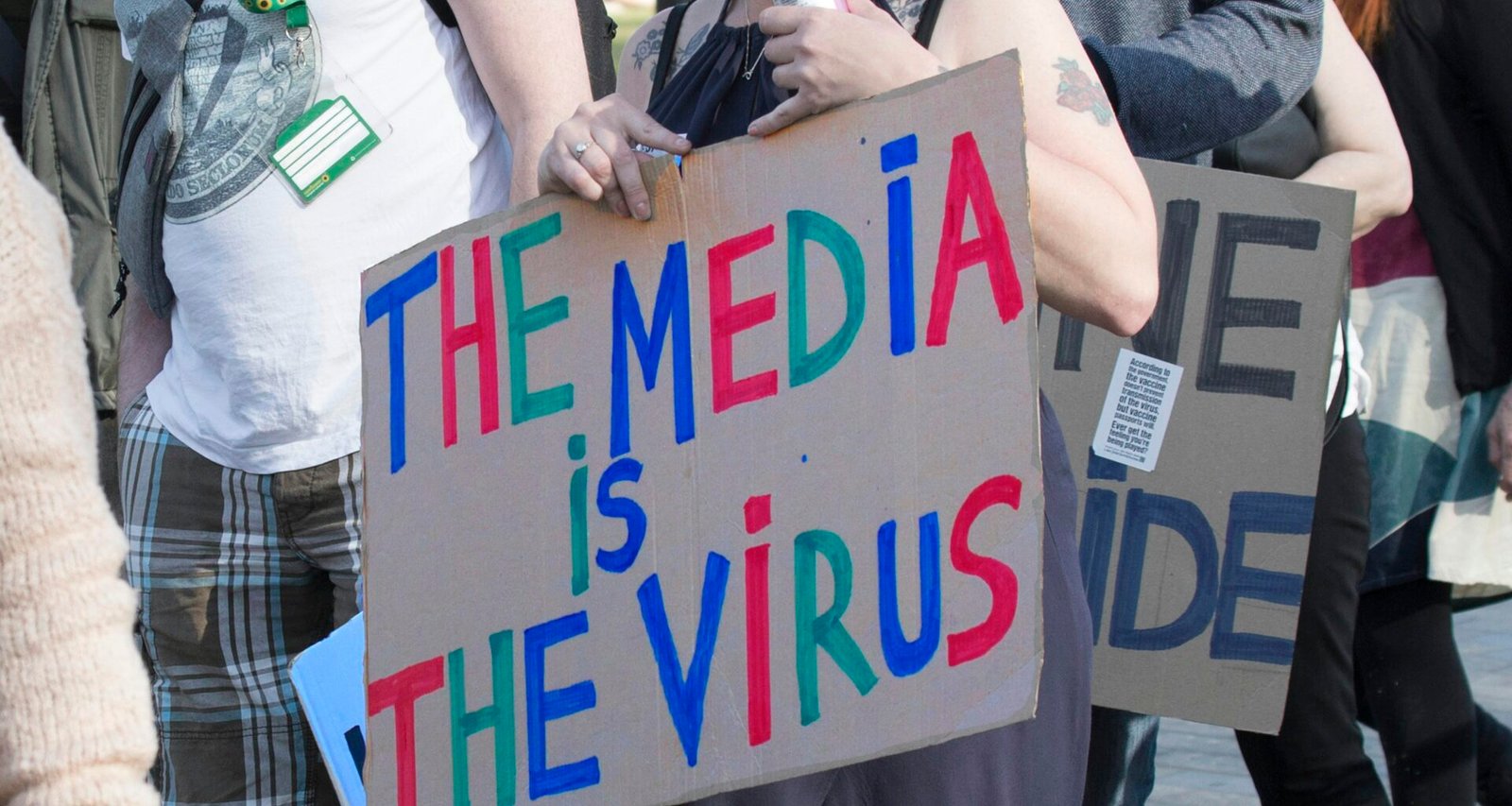 Person hält ein weiß-blaues Schild mit dem Text 'I’m a little man' in den Händen, neutrale Umgebung