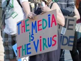 Person hält ein weiß-blaues Schild mit dem Text 'I’m a little man' in den Händen, neutrale Umgebung