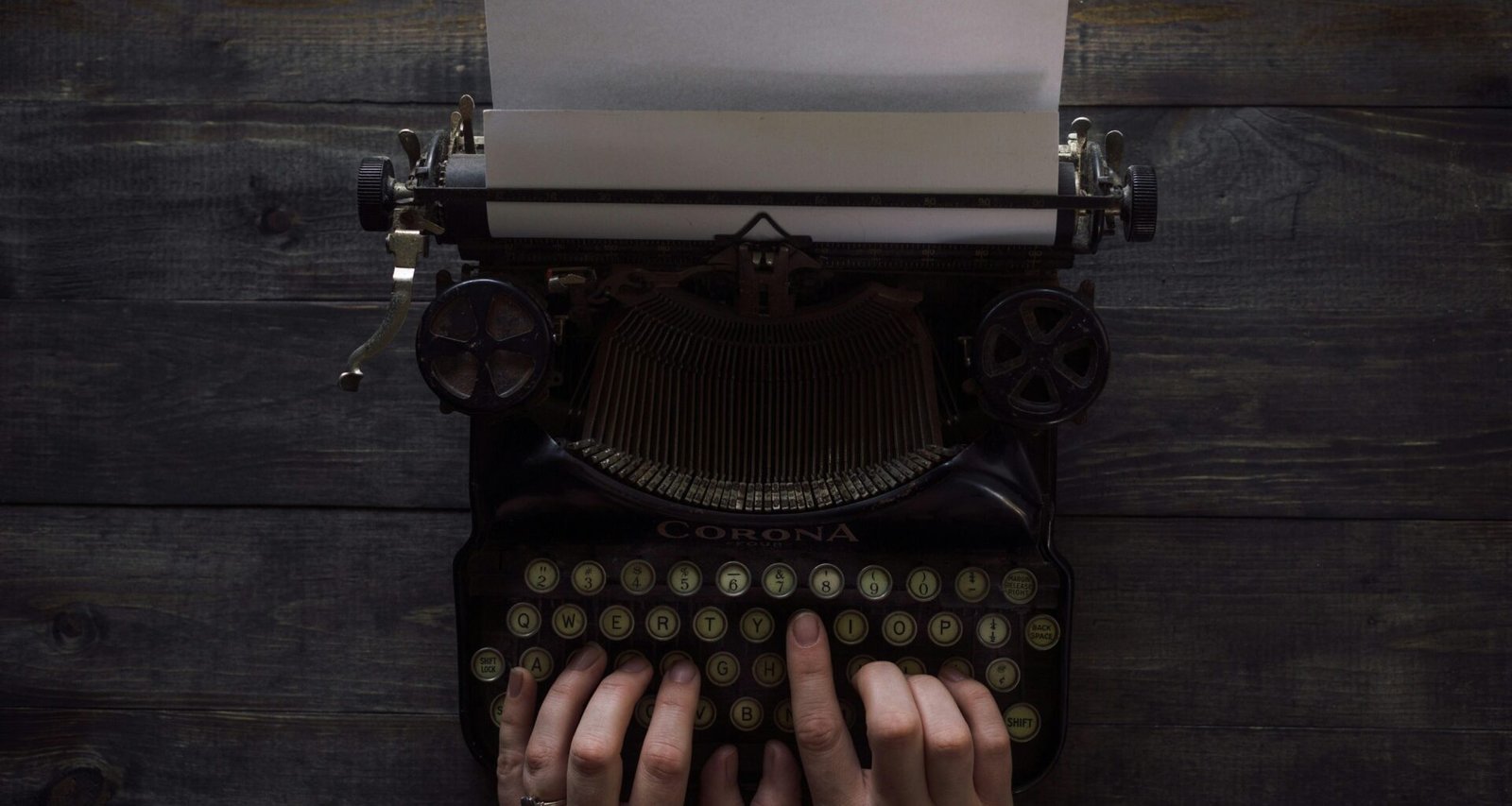 Person hält eine weiße und schwarze Schreibmaschine in den Händen, als Sinnbild für kreatives Schreiben und digitale Inhalte.