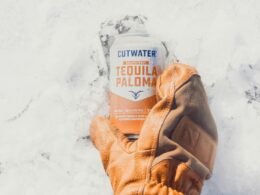 Person mit braunen Lederhandschuhen hält eine weiß und orange beschriftete Dose, Nahaufnahme als Beitragsbild zu Technologiethemen