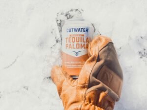 Person mit braunen Lederhandschuhen hält eine weiß und orange beschriftete Dose, Nahaufnahme als Beitragsbild zu Technologiethemen