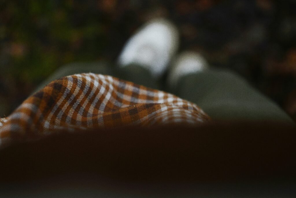 Person in kariertem Oberteil und grüner Hose mit weißen Schuhen steht auf Gehweg, trendiger Streetstyle-Look.