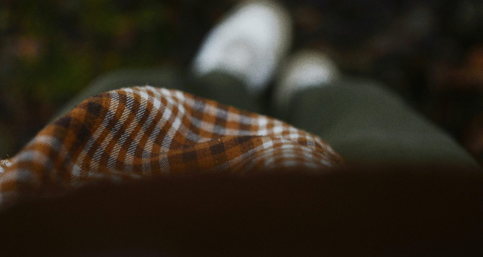 Person in kariertem Oberteil und grüner Hose mit weißen Schuhen steht auf Gehweg, trendiger Streetstyle-Look.