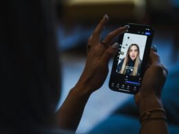 Person hält ein Smartphone in der Hand und sieht sich ein Video auf dem Bildschirm an, Fokus auf das Gerät und die Nutzerinteraktion