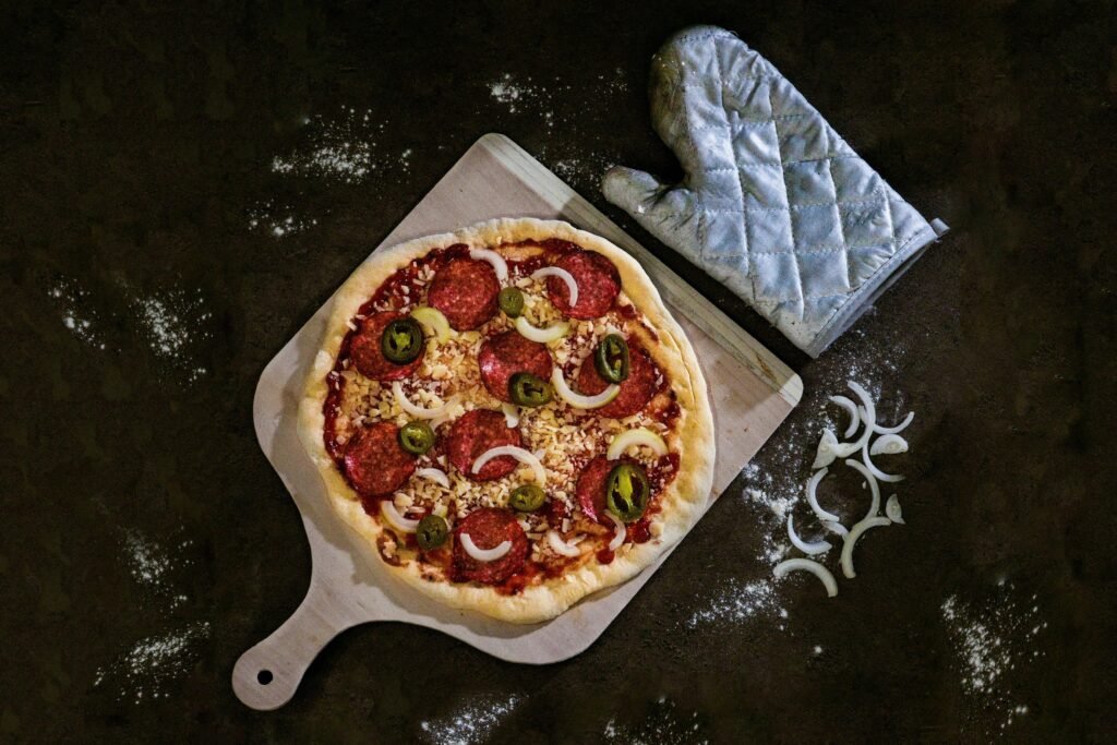 Frisch gebackene Pizza, serviert auf einem braunen Holztablett, von oben fotografiert auf hellem Untergrund