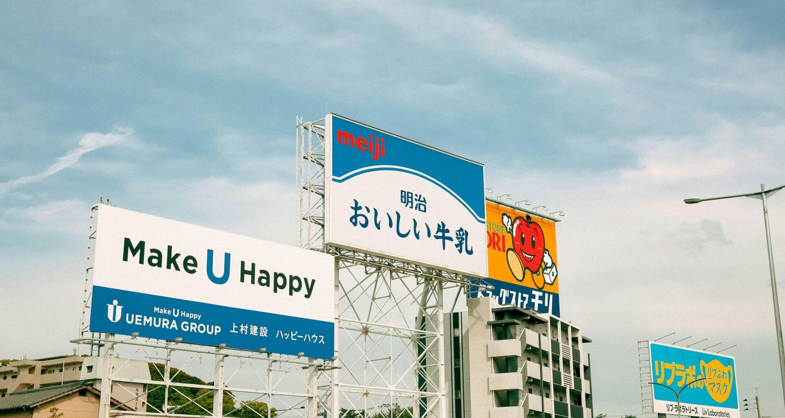 Mehrere große Leuchtreklamen mit japanischer Schrift sind in einer urbanen Umgebung deutlich sichtbar.