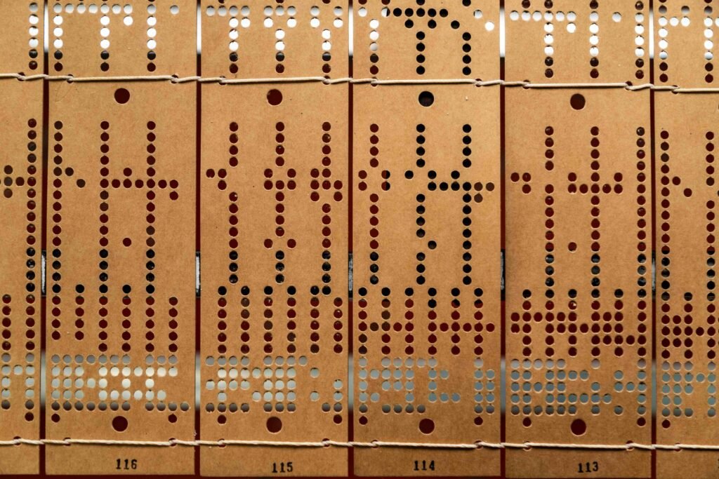 Mehrere Reihen alter gestanzter Lochkarten zur Datenspeicherung, nebeneinander angeordnet, historische Informationstechnologie