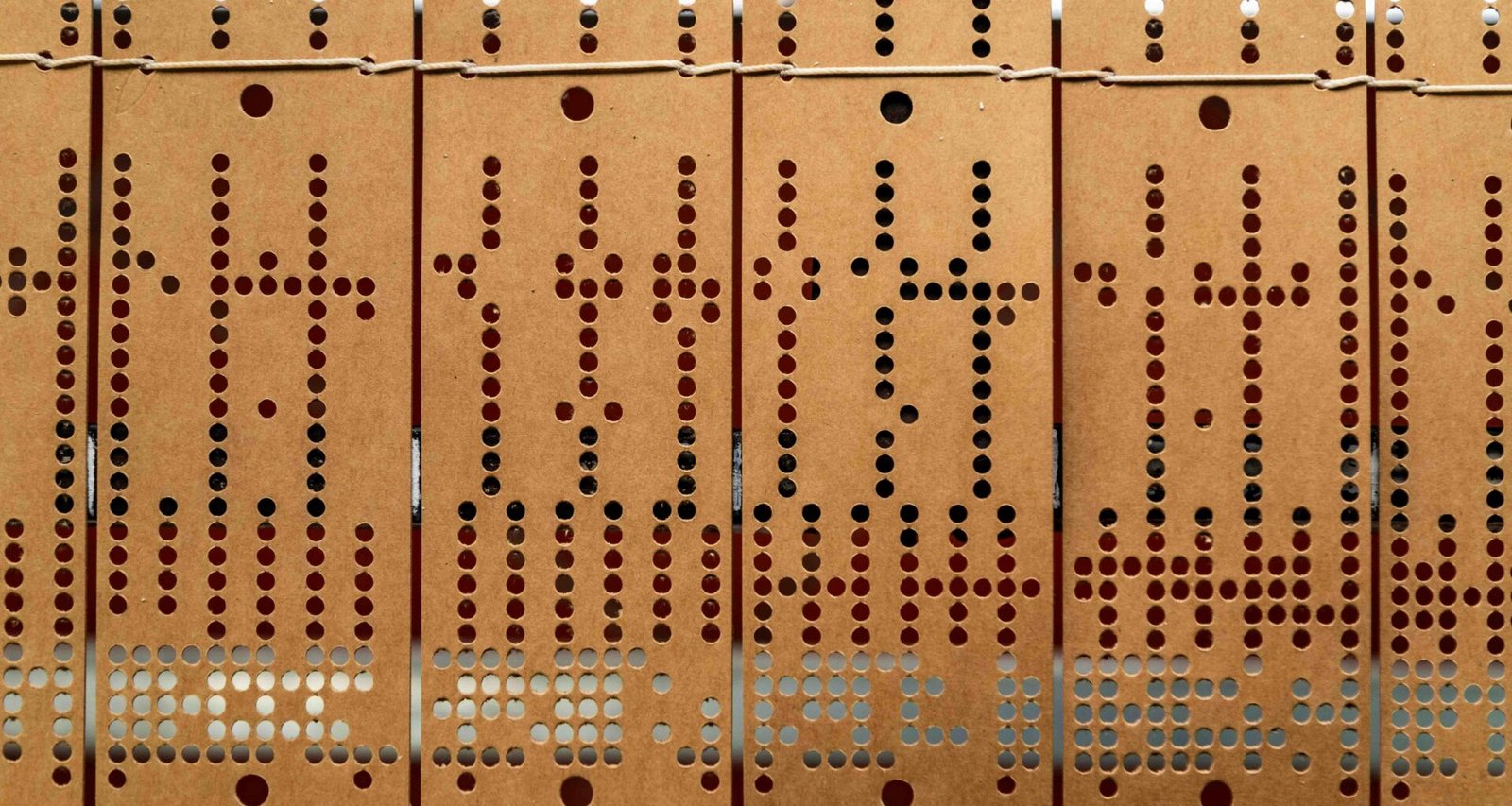 Mehrere Reihen alter gestanzter Lochkarten zur Datenspeicherung, nebeneinander angeordnet, historische Informationstechnologie