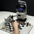 Roboterarm, der beim Schachspielen mit einer menschlichen Hand konkurriert, symbolisiert KI-Entwicklung und Technologie