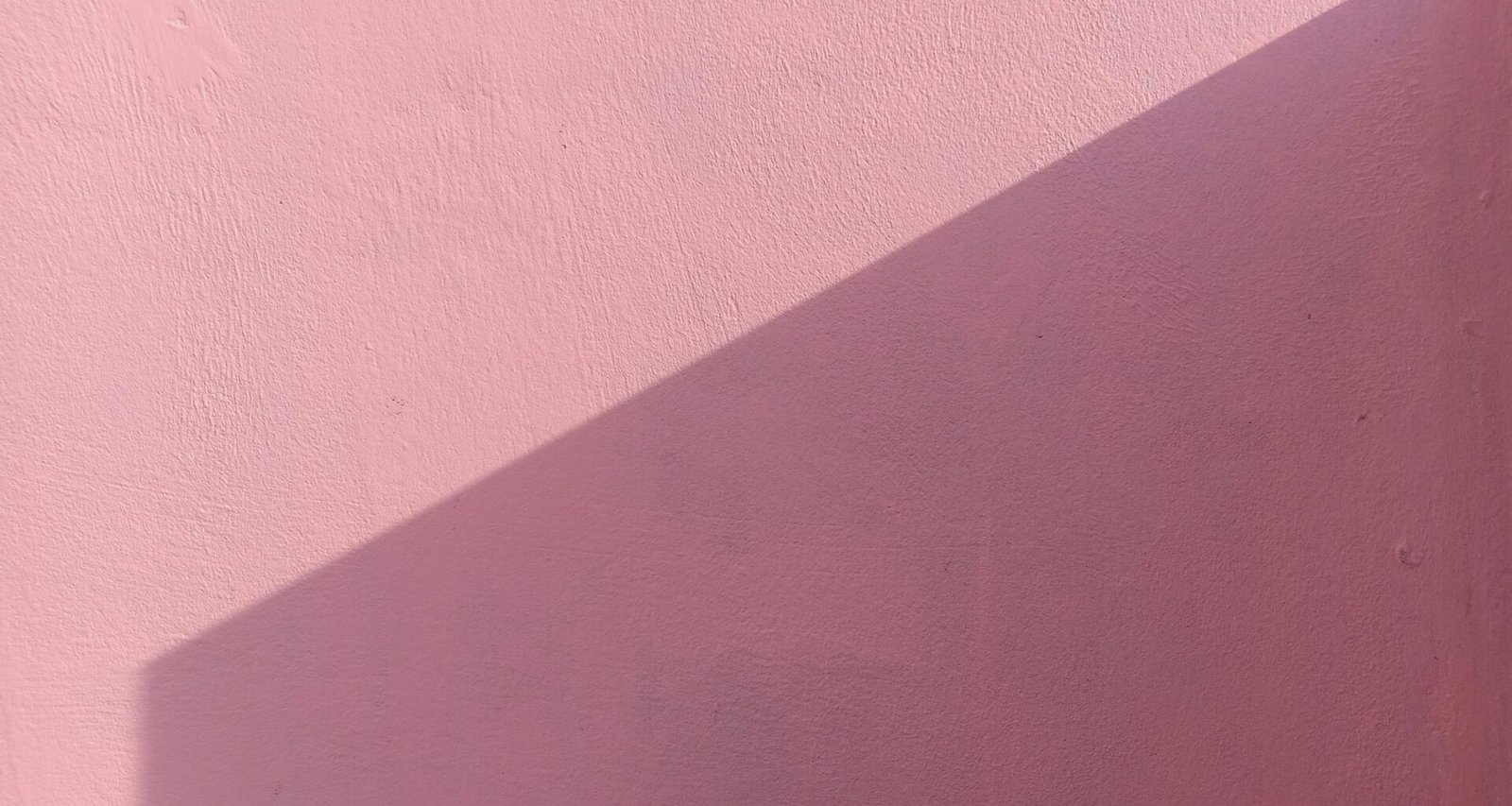 Rosa gestrichene Wand mit frischer, gleichmäßiger Farbschicht und klaren Kanten, fotografiert von Yeon Li