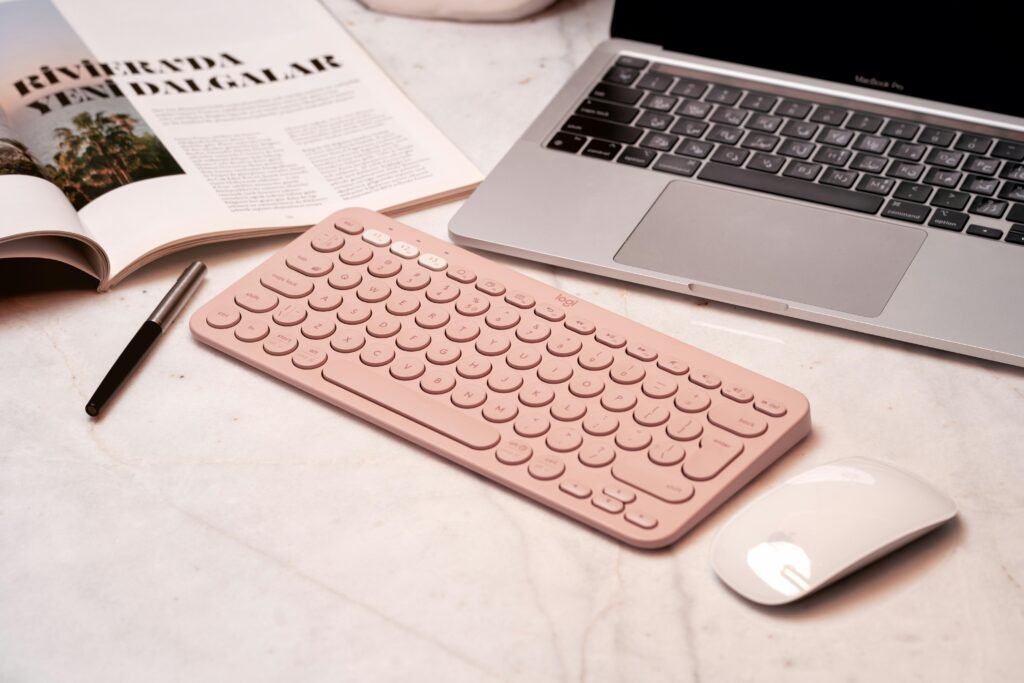 Pinke Tastatur, Maus und ein Laptop stehen ordentlich auf einem Schreibtisch in einem modernen Home-Office-Umfeld