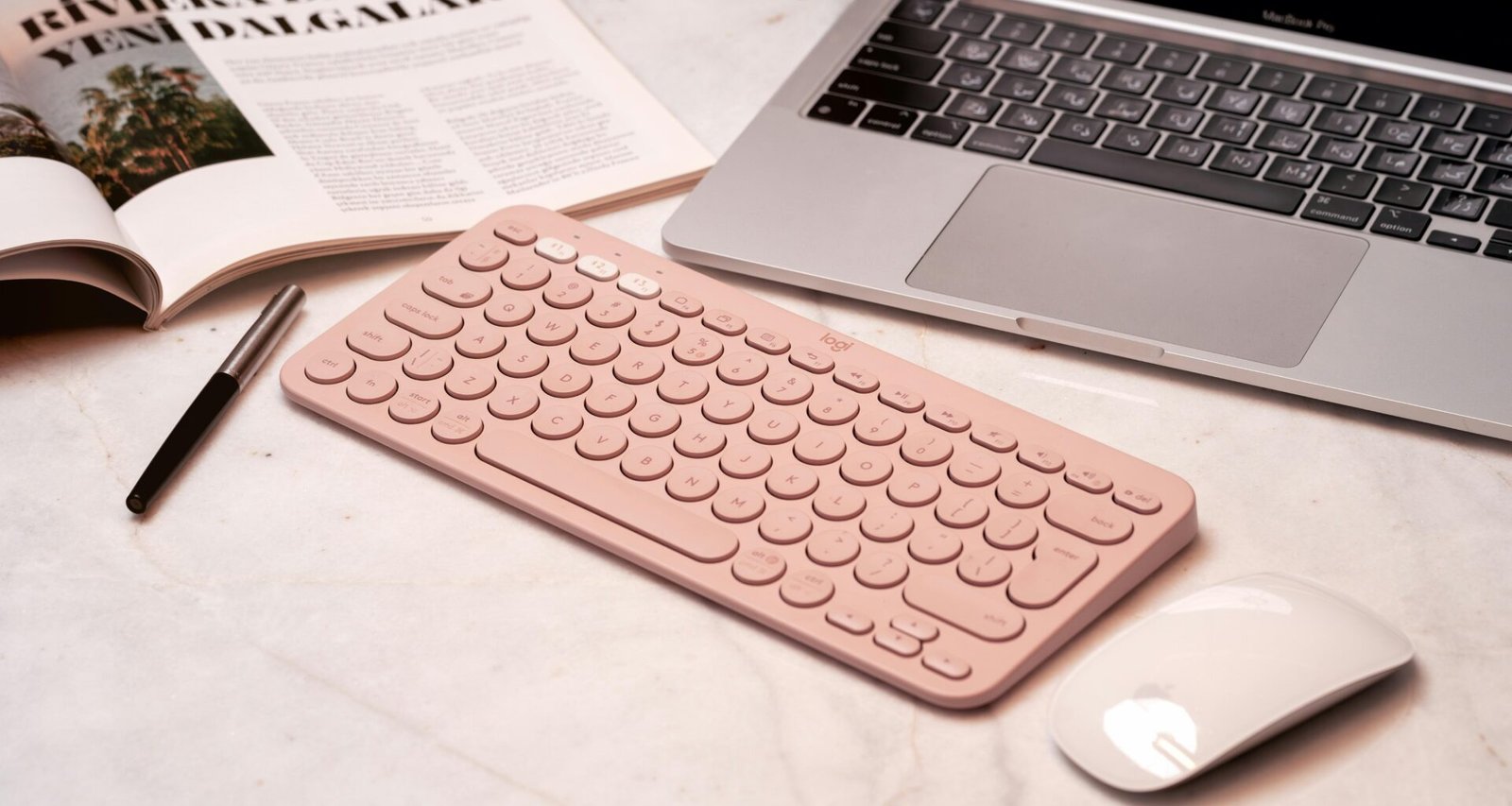 Pinke Tastatur, Maus und ein Laptop stehen ordentlich auf einem Schreibtisch in einem modernen Home-Office-Umfeld
