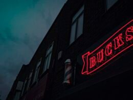 Rot-weißes Coca Cola Neon-Leuchtschild in dunkler Umgebung, Symbol für Markenpräsenz und Retro-Stil.