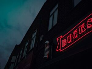 Rot-weißes Coca Cola Neon-Leuchtschild in dunkler Umgebung, Symbol für Markenpräsenz und Retro-Stil.