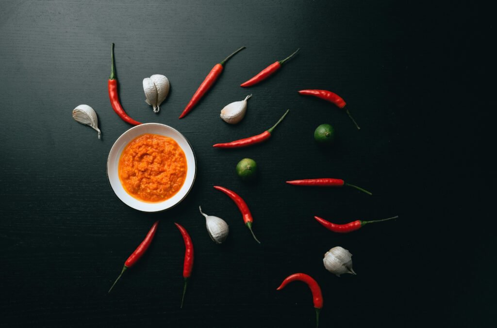 Rote und grüne Chilischoten liegen nebeneinander in einer weißen Keramikschale auf hellem Hintergrund.