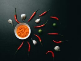 Rote und grüne Chilischoten liegen nebeneinander in einer weißen Keramikschale auf hellem Hintergrund.