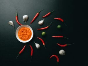 Rote und grüne Chilischoten liegen nebeneinander in einer weißen Keramikschale auf hellem Hintergrund.