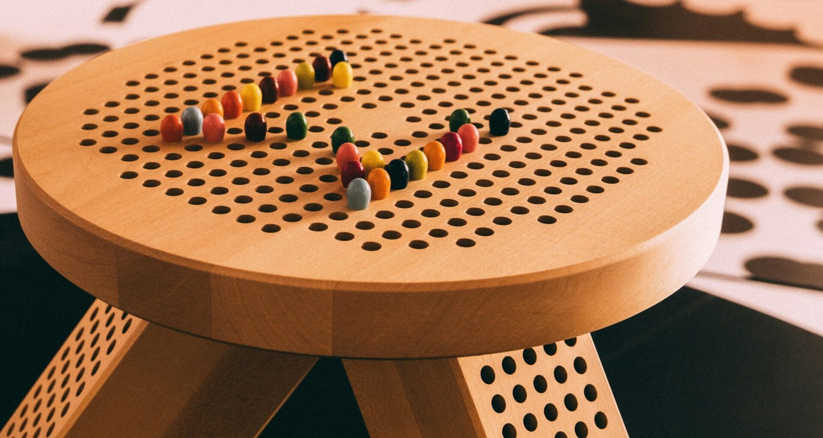 Rote und gelbe Perlen liegen auf einem braunen, runden Holztisch in einer hellen Umgebung.