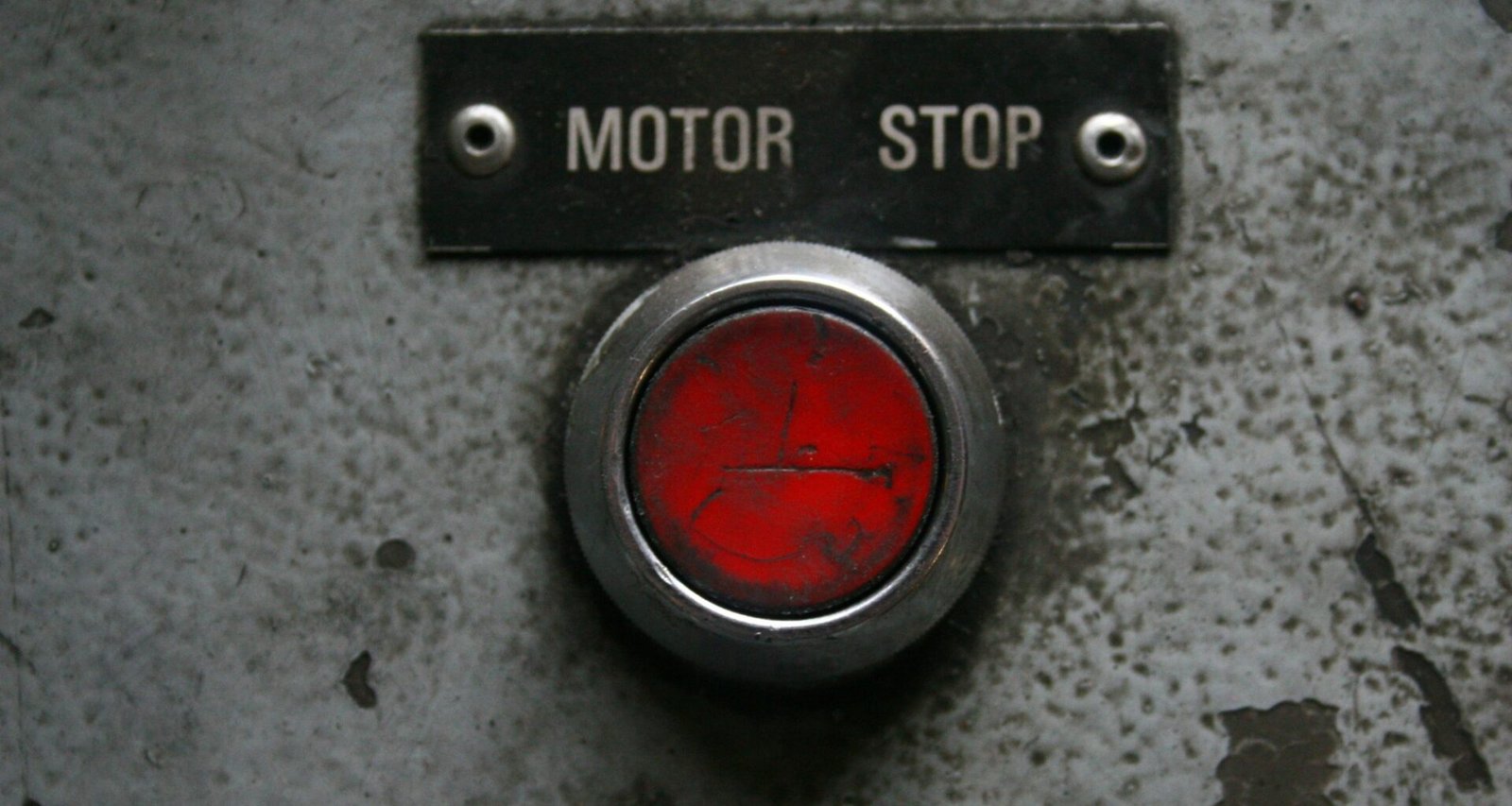 Roter Not-Aus-Knopf auf einer industriellen Metallplatte, symbolisch für Sicherheit und Kontrolle in technischen Systemen