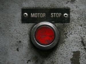 Roter Not-Aus-Knopf auf einer industriellen Metallplatte, symbolisch für Sicherheit und Kontrolle in technischen Systemen