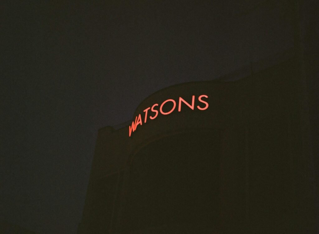 Rote Watsons Neon-Leuchtreklame leuchtet an einer urbanen Wand und betont die Bedeutung von Markenpräsenz im öffentlichen Raum