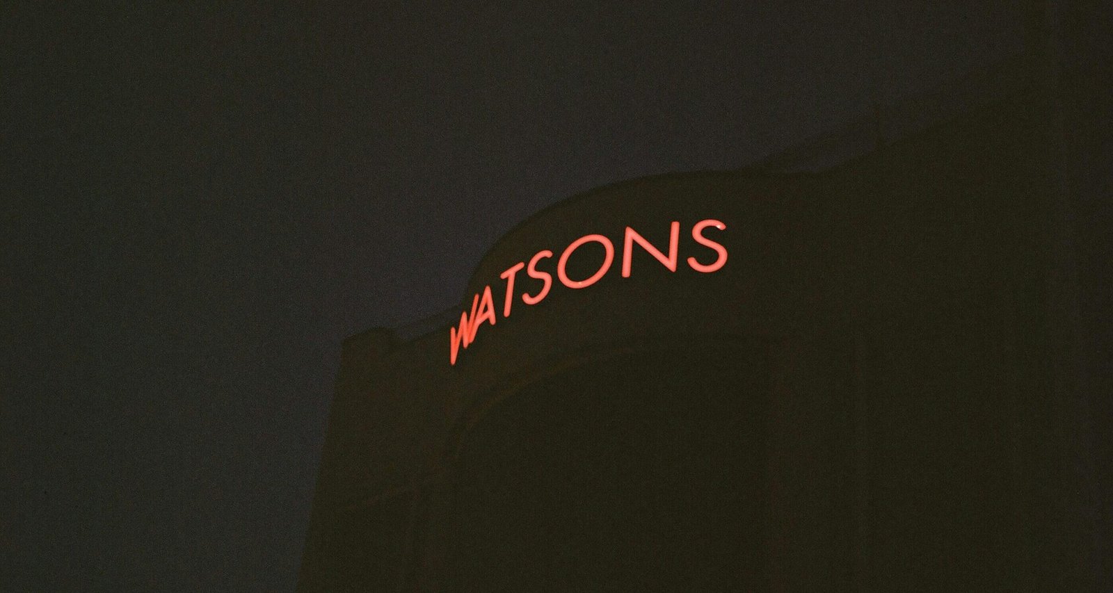 Rote Watsons Neon-Leuchtreklame leuchtet an einer urbanen Wand und betont die Bedeutung von Markenpräsenz im öffentlichen Raum