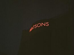 Rote Watsons Neon-Leuchtreklame leuchtet an einer urbanen Wand und betont die Bedeutung von Markenpräsenz im öffentlichen Raum