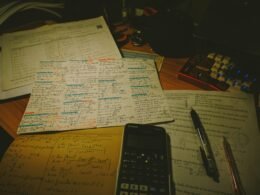 Ordentlicher Schreibtisch mit Papieren, Taschenrechner und verschiedenen Stiften für Büro- oder Homeoffice-Arbeiten