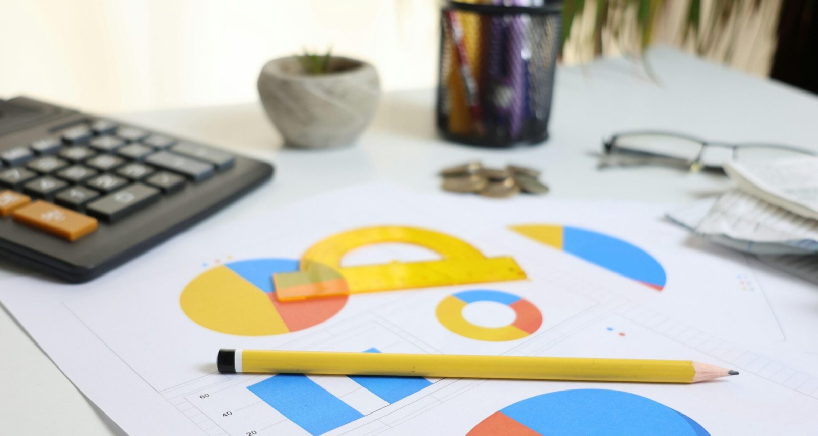 Schreibtisch mit Taschenrechner, ausgedruckten Charts und Bleistift, bereit für die Analyse von Geschäftsdaten