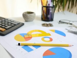 Schreibtisch mit Taschenrechner, ausgedruckten Charts und Bleistift, bereit für die Analyse von Geschäftsdaten